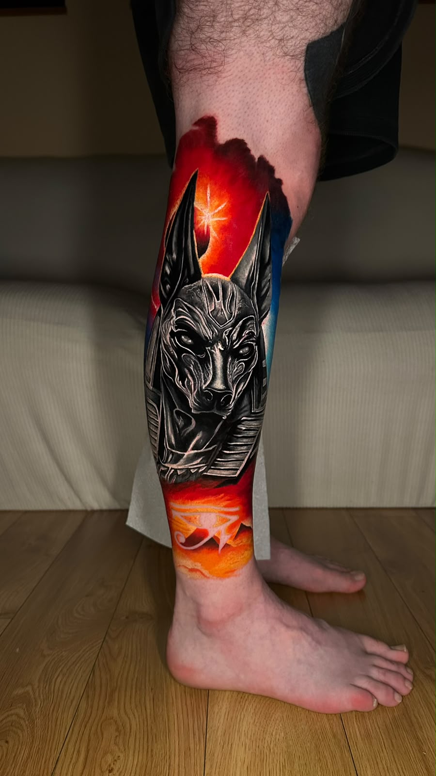 Color realism Anubis calf tattoo with red and orange background