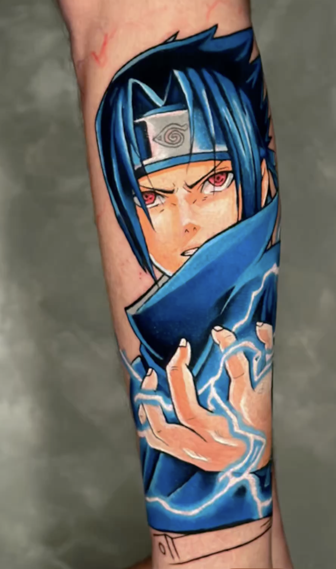 Vivid blue Sasuke Uchiha anime forearm tattoo with lightning